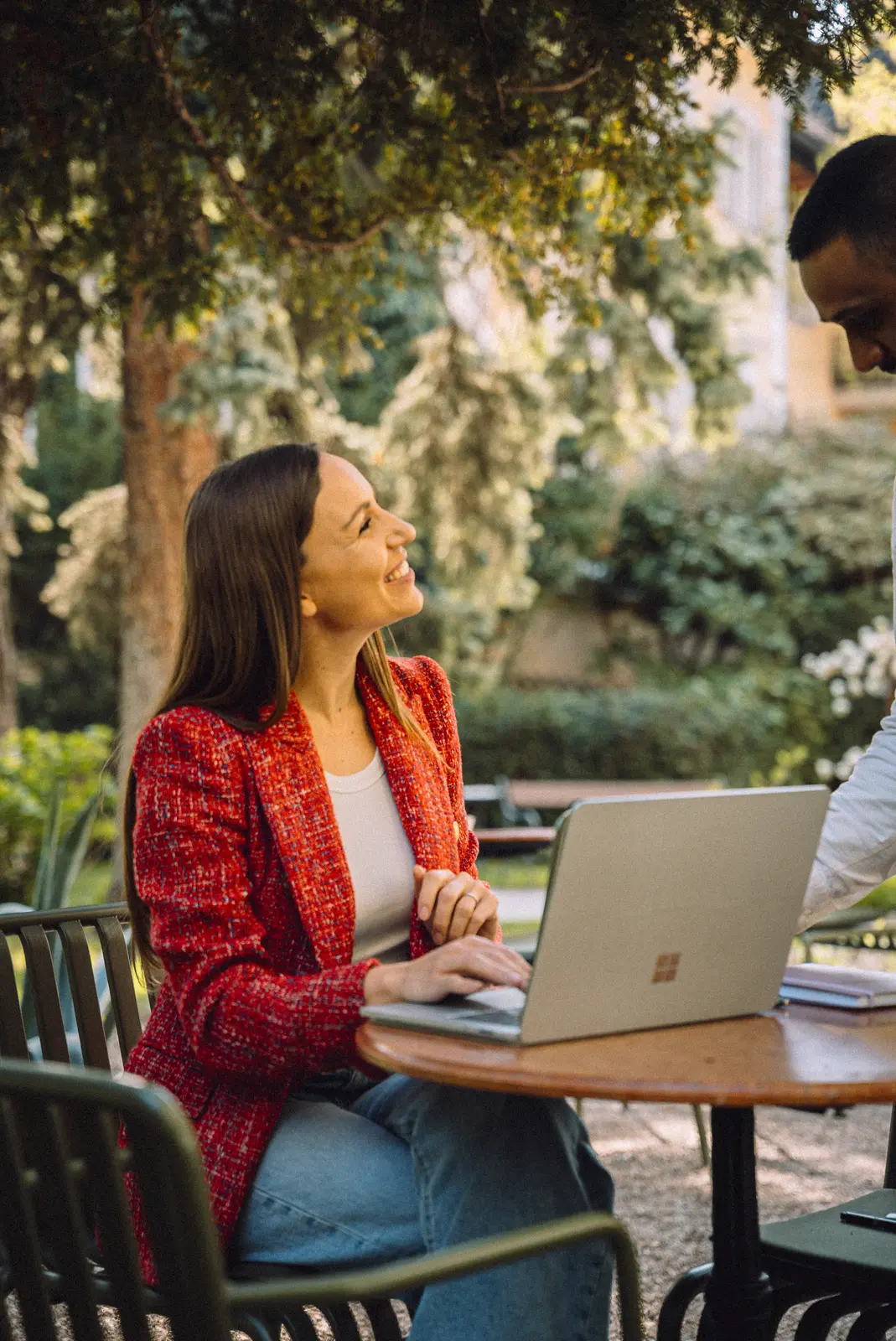 Lena arbeitet am Laptop an einem Tisch im Gartencafé