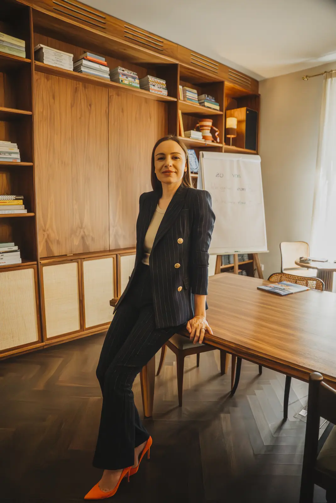 Lena lehnt an einem Tisch in einem Seminarraum mit Flipchart